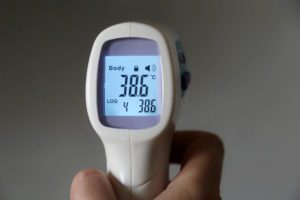 High body temperature, digital display of isometric non-contact thermometer in hand a person holding a digital thermometer displaying the body temperature